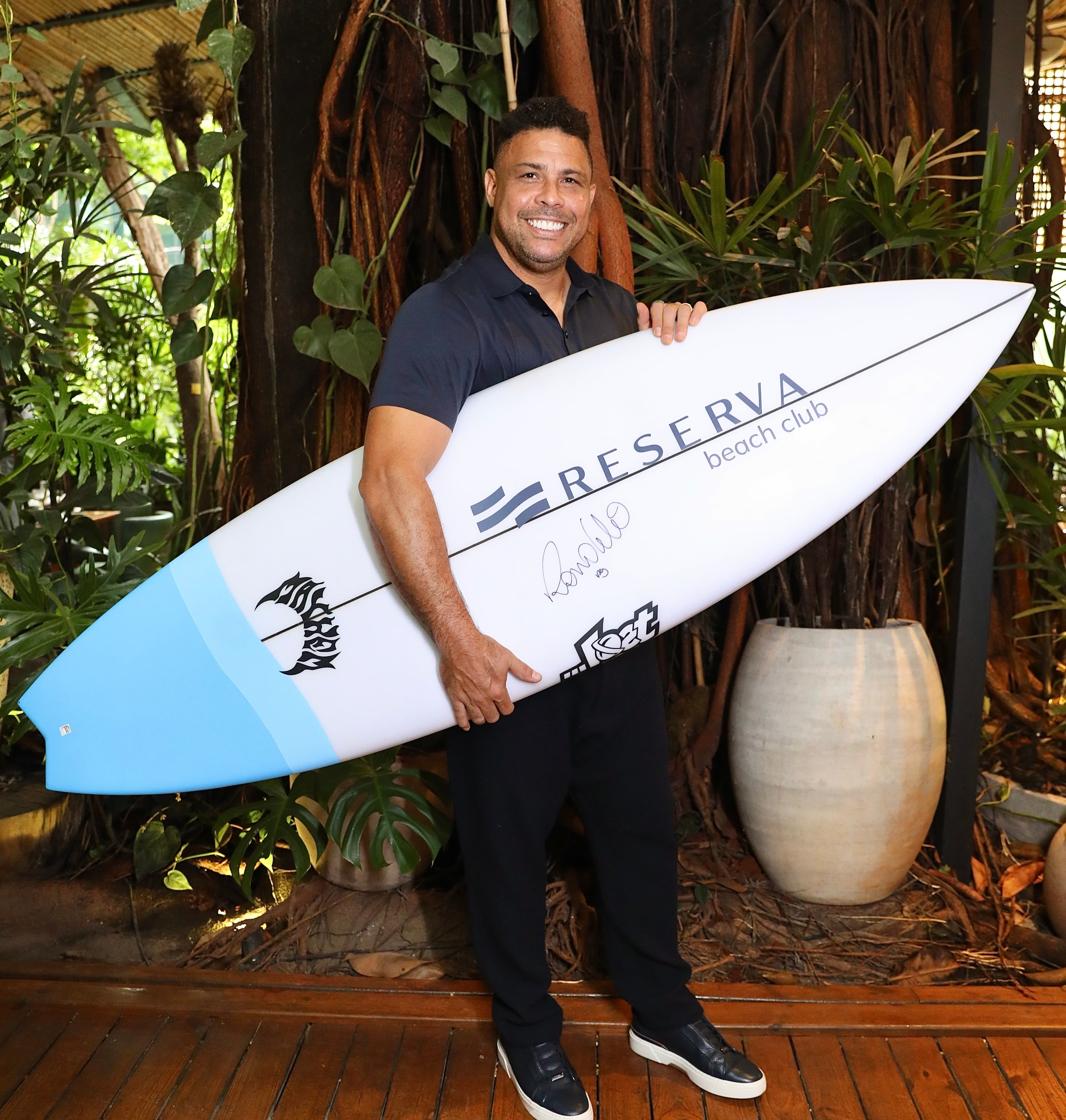 Ronaldo Nazário segurando prancha de surf do Reserva Beach Club
