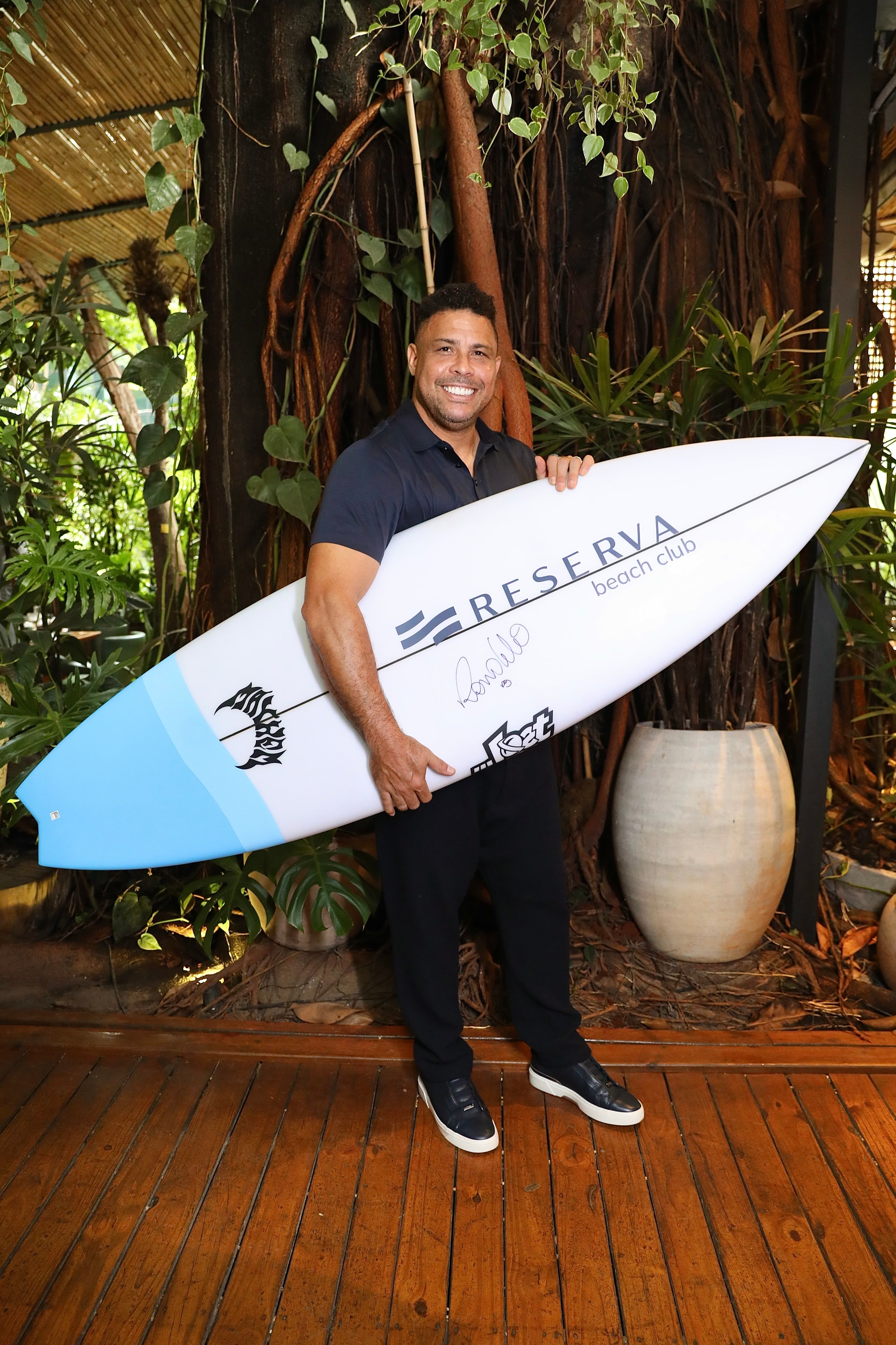 Ronaldo Nazário segurando prancha de surf do Reserva Beach Club